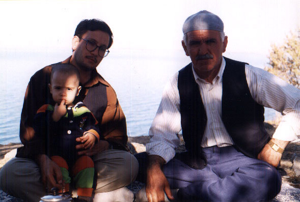 father, son and grandfather sit on a blanket drinking tea