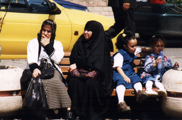 A woman in a black chador sits with her family